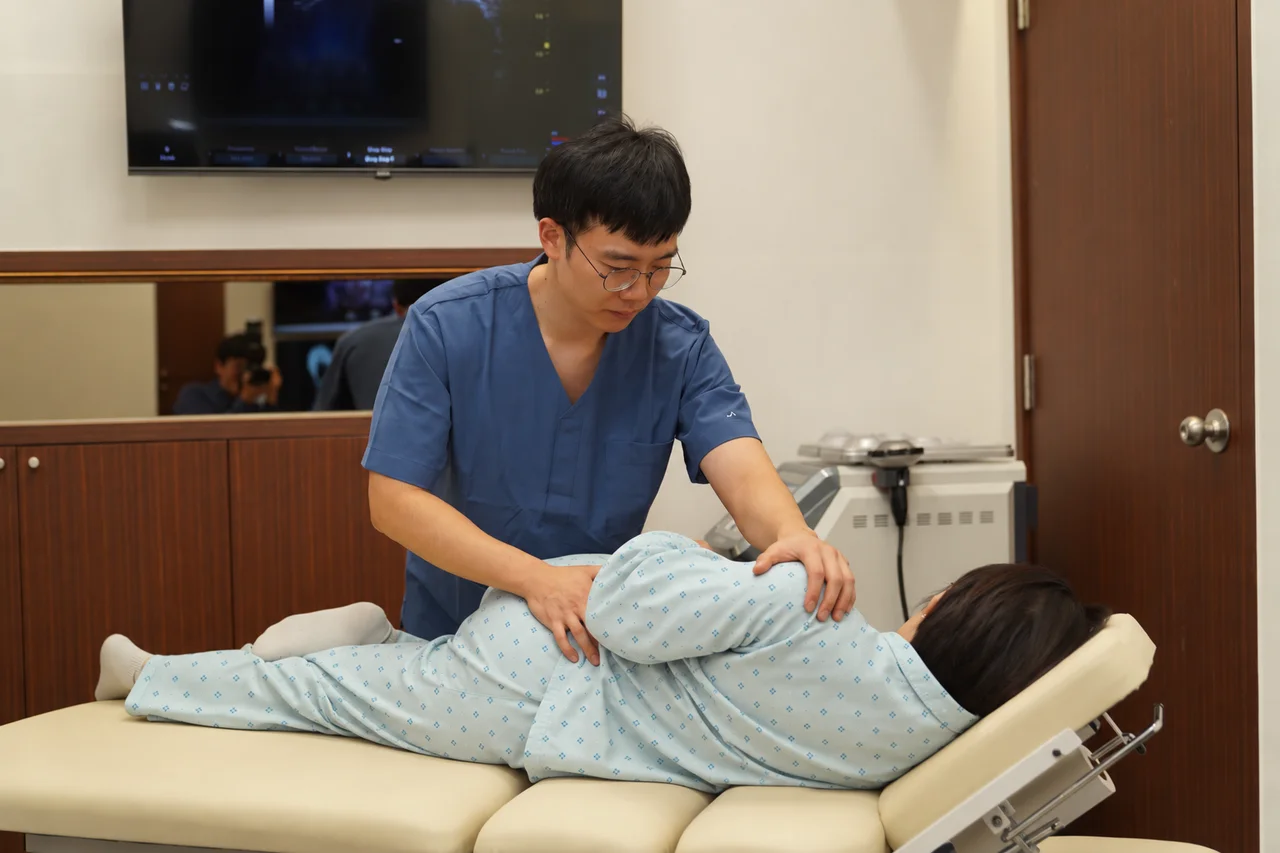 옆으로 누운 환자의 몸을 지지하며 추나치료를 진행하는 모습